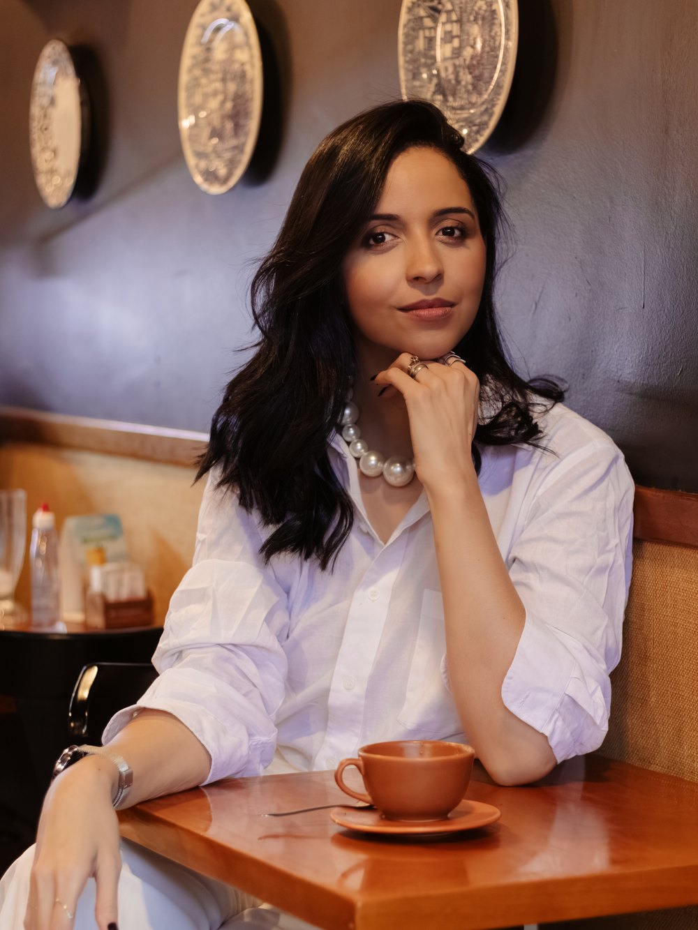 Jessica Araujo sentada em uma mesa de café